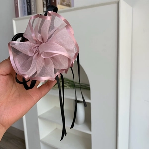 Dettaglio della pinza per capelli con fiore in organza rosa e lunghi nastri neri decorativi