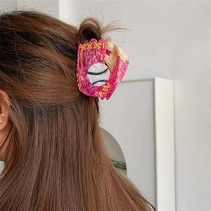 Detailed view of creative acetate pink baseball glove hair claw clip worn on hair