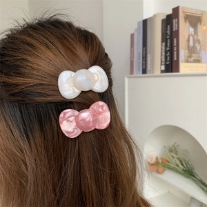 Pearlescent candy-colored acetate bow hair clips for women in white and pink
