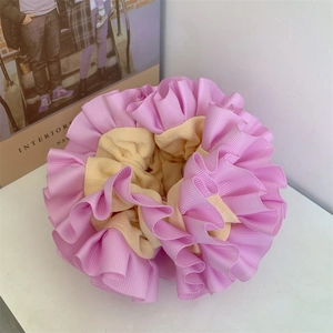 Close-up of dual-tone pink and yellow pleated fabric scrunchie with layered ruffle texture