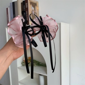 Dettaglio dei fermagli per capelli con fiocchi in organza rosa e nastri di seta nera