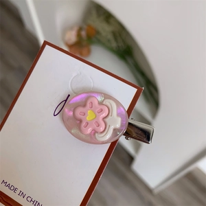 Dettaglio di fermaglio per capelli rosa perlato con fiori e nuvole su cartoncino