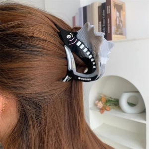 Detail showing marble grey and black fish-shaped hair claw clip worn on a woman's hair