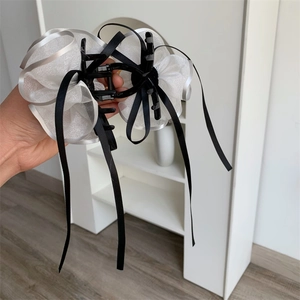 Dettaglio del grande fermaglio per capelli con fiore in organza bianca e nastri di raso