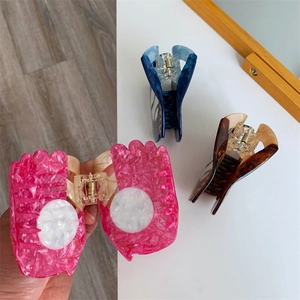 Detailed view of acetate hair claws in pink, blue, and brown with pearl accents