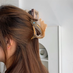 Detail view of the amber marble fish-shaped hair claw clip styled on a model's hair