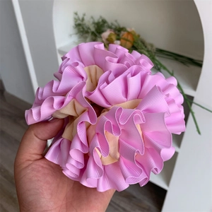 Detailed view of layered pink and beige ruffled fabric scrunchie with ribbed texture