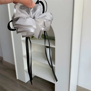 Dettaglio molletta per capelli a fiore in organza bianca con nastri neri e bordi argento