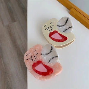 Detail of creative cream and pink marble acetate hair claws with baseball stitch design