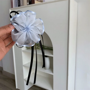 Dettaglio dell'elegante fermaglio per capelli in organza con nastri neri e petali strati