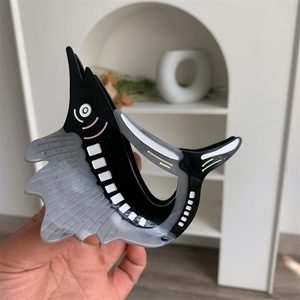 Detail of sailfish-shaped acetate hair claw with marble texture and polished finish