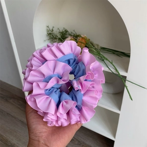 Close-up of pink and blue pleated scrunchie showing ribbed texture and dual-tone stitching