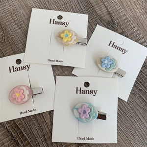 Set di 4 mollette per capelli in resina colorata con fiori su superficie di legno
