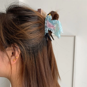 Haarklammer aus blauem Acetat in Schwalbenform zeigt elegantes Design auf braunem Haar