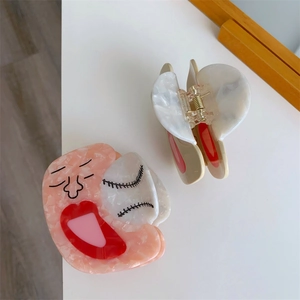 Close-up of acetic acid hair claw clip with abstract face design and marble texture