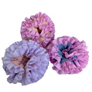 Three oversized pleated scrunchies in pastel macaron colors with soft ribbed fabric texture