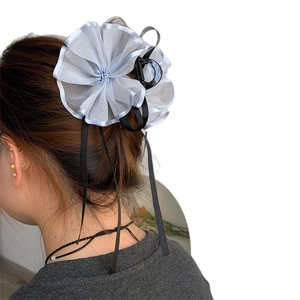 Pinza per capelli con fiore in rete azzurra e lunghi nastri neri indossata dal modello