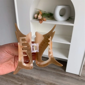 Close-up of amber acetate hair claw clip featuring a unique fish-shaped design with spring