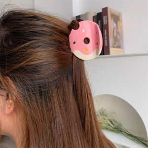 Detail view of pink and beige donut hair claw clip with colorful sprinkles on model