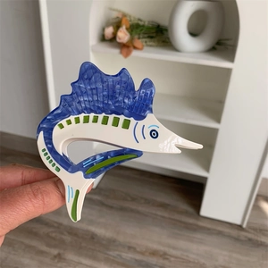 Detailed macro view of a fish-shaped acetate hair claw clip with blue and white textures