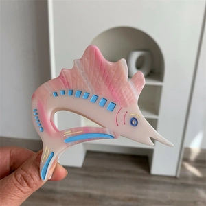 Detail of pink marble acetate swordfish hair claw clip with blue and yellow accents