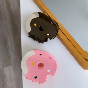 Detail of donut-shaped hair clips in pink and brown with sprinkle texture design