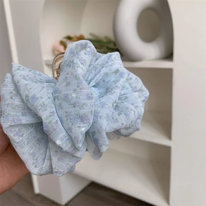 Close-up of a blue floral fabric hair claw clip featuring delicate pleated mesh detail