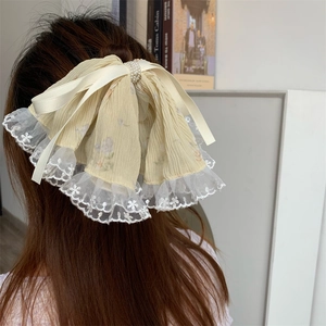 Detail of floral fabric bow hair claw with white embroidery lace and pearl embellishments
