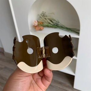 Detail of donut shaped chocolate brown and cream hair claw clip with spring hinge