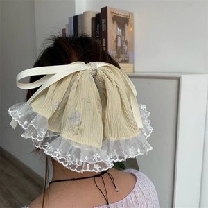 Detail of lace hair claw clip with floral fabric bow and pearl beads in hair