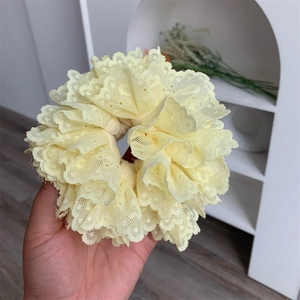 Close-up of pale yellow lace scrunchie with layered hollow mesh and ruffled edges