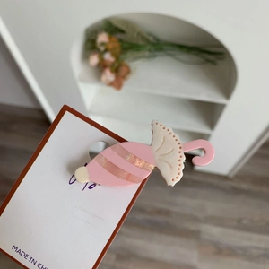 Detailaufnahme einer rosa regenschirmförmigen Haarspange aus Acetat auf weißer Karte