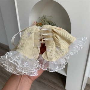 Close-up of yellow fabric hair claw with white embroidery lace and pearl details