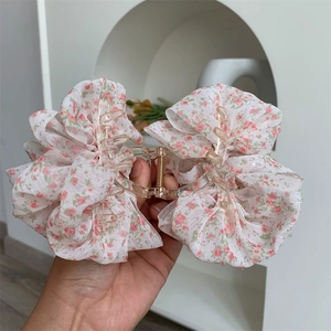 Detailed close-up of floral fabric mesh shark hair claw clip with golden metal spring