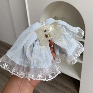 Detail of light blue pleated lace hair claw clip with white floral embroidery and pearl