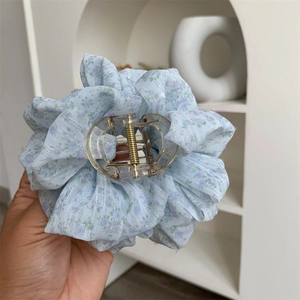 Detail of light blue floral chiffon hair claw clip with transparent acrylic and gold spring