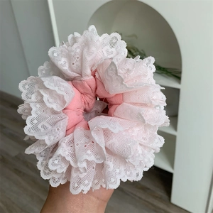 Close-up of pink and white lace scrunchie with layered hollow design and soft ruffled texture