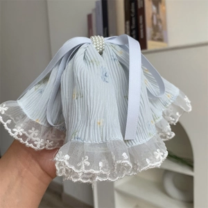 Close-up of light blue floral lace hair claw with white pearls and flowing ribbons