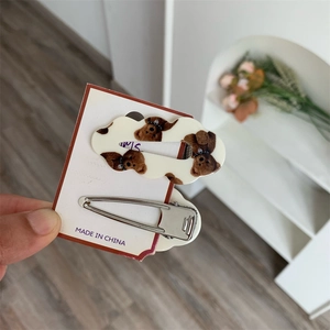 Gros plan d'une barrette à motif d'ours et d'un clip BB en métal argenté sur carte