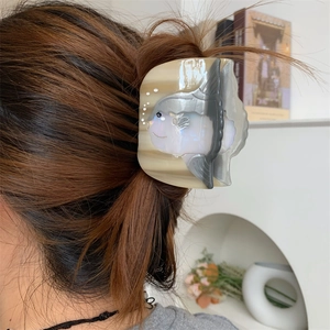 Vue détaillée de la pince à cheveux en forme de mola mola portée sur cheveux bruns