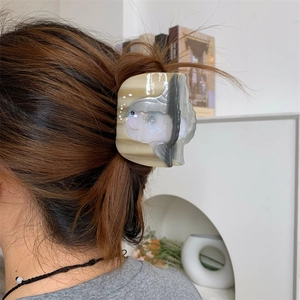 Vue détaillée d'une pince à cheveux en acétate motif poisson-lune portée sur les cheveux