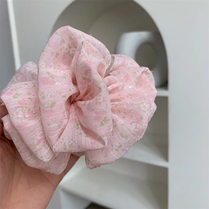 Detailed macro view of large pink floral scrunchie with pleated chiffon fabric texture