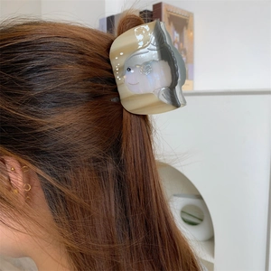 Détail de la pince à cheveux en forme de môle en acétate portée sur cheveux