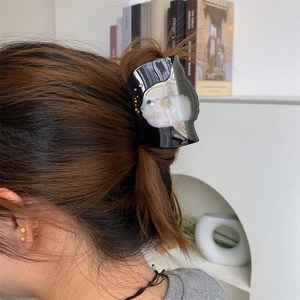Vue détaillée de la texture perlée et du contour doré sur la pince à cheveux en acétate