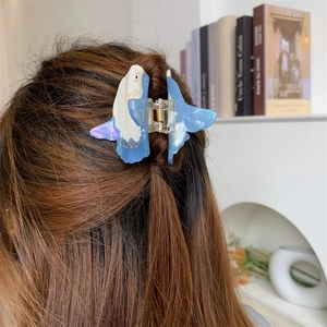 Detail view of a sunfish acetate hair claw clip with blue gradient and purple pearlescent finish