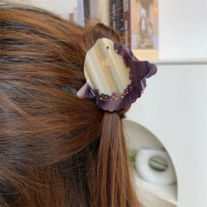 Detailed close-up of fish-shaped acetate hair claw with marble texture and golden dots