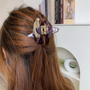Detail view of purple and beige butterfly claw clip in acetate on brown hair
