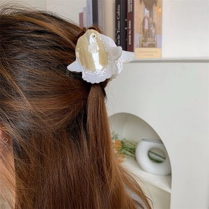 Detail of fish-shaped acetate hair claw clip in pearl white and brown on brunette hair
