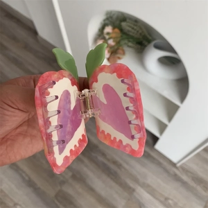 Close-up of pink marble heart hair claw clip with green leaf and purple details