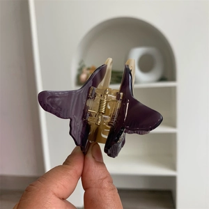 Detail of a purple and beige butterfly hair claw clip with golden metal spring